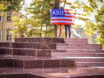 Sorority sister with flag posing on a fountain on campus
