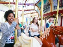 three students sitting on carousel horses at the Cleveland History Center