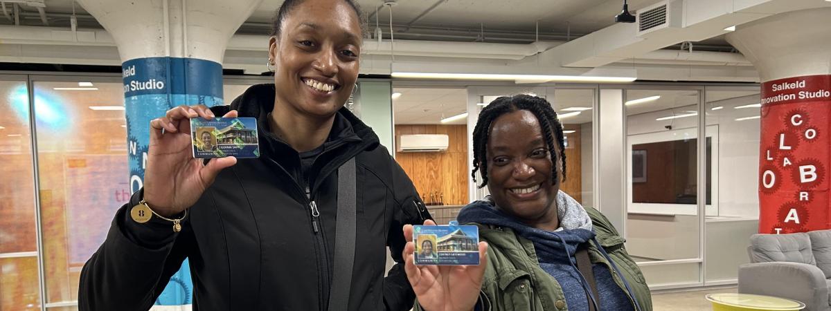 Two smiling women holding up community cards