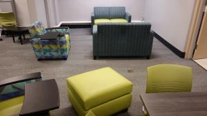 Glaser House Basement Group Study Lounge showing chairs with attached desks, tables, and foot stools