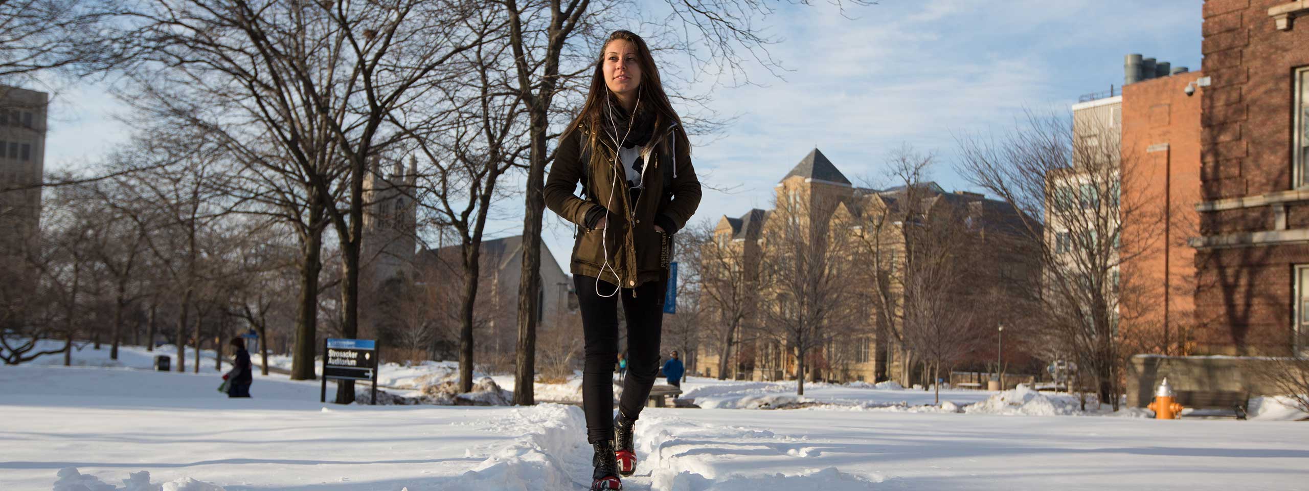 Photo of female student walking across campus surrounded by snow