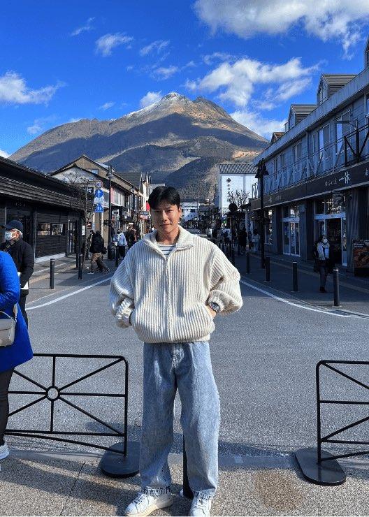 Junwoo Shim standing in front of a large mountain with a blue sky over him