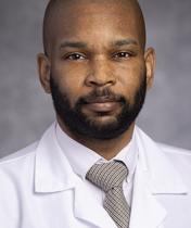 African American man with beard in white medical coat.