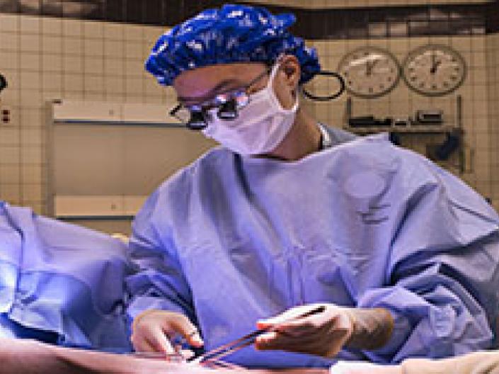 Virginia Wong, MD OR Photo operating on arm of patient with blue surgical gown.