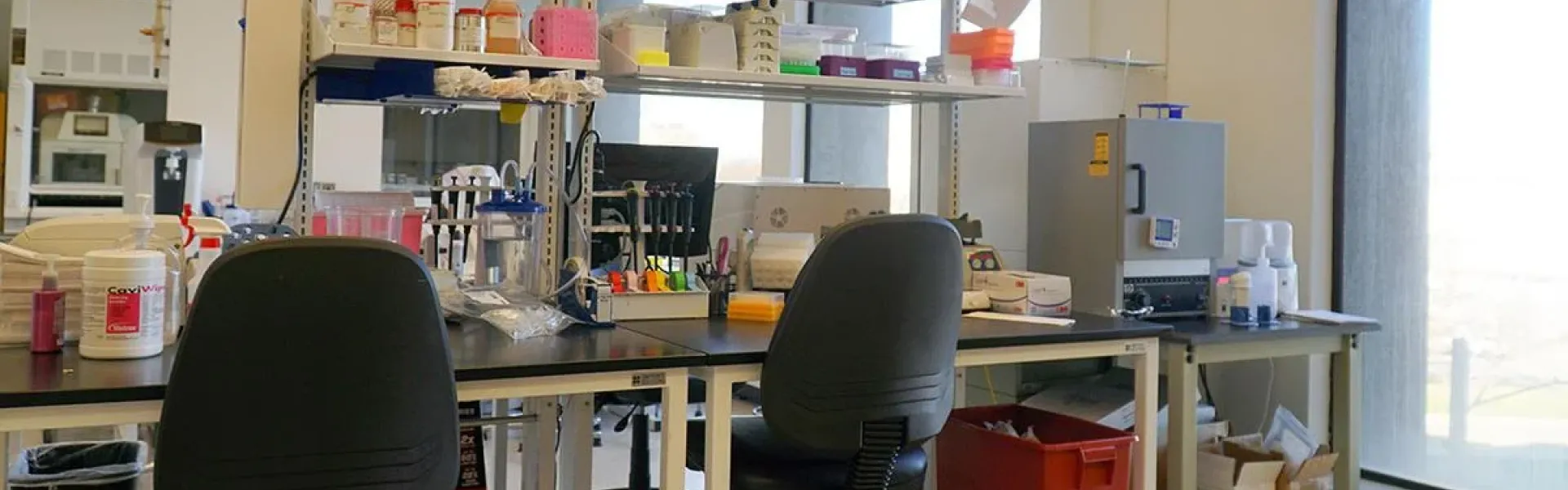 A lab room with a desk and shelves with objects on it