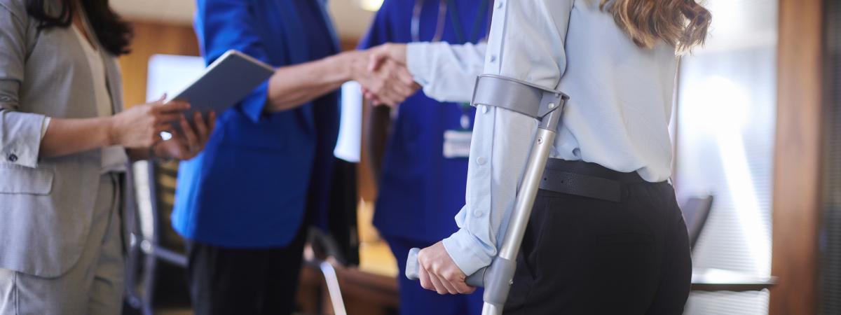 Cropped image of an injured worker on a crutch meeting with doctors and the company representative