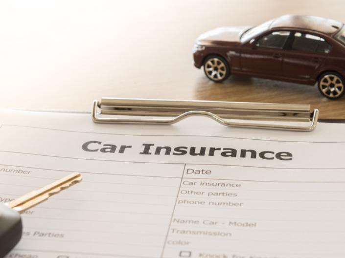 Close up of car insurance application form with car model and key remote on desk