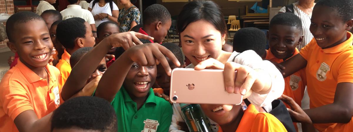 Social work student takes a selfie with a group of students in Ghana