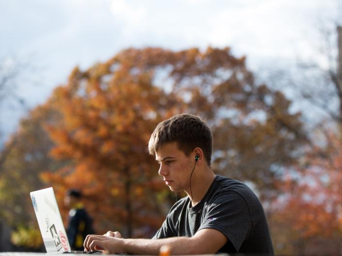 Student sitting outside on computer