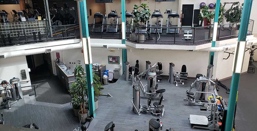 An aerial view of the inside of One to One Fitness Center, with green pillars and two levels of fitness equipment.