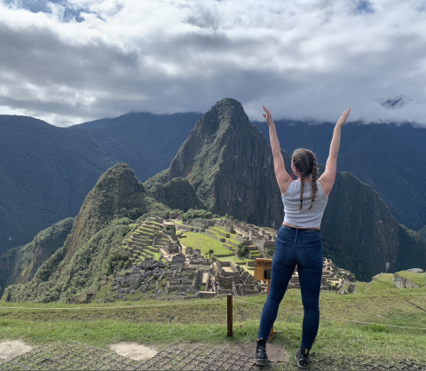 CWRU student standing in front of Maccu Picchu, Peru with arms raised