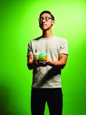 A photo of Chris Hadiono holding a model of a brain