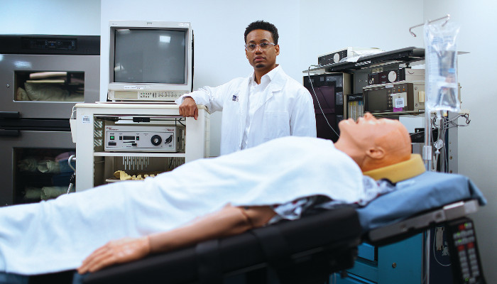 A photo of Ronald Hickman Jr. next to a medical dummy on a gurney