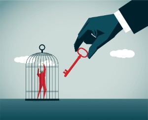 An illustration of a large hand holding a red key out to a tiny man in a birdcage