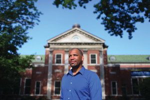 A photo of CWRU biology faculty Emmitt Jolly standing in front of a brick school building