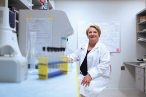 A photo of CWRU nursing faculty Rebecca Darrah sitting at a lab station wearing a lab coat.