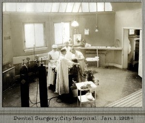 Three dentists and a nurse standing over a patient in an exam room