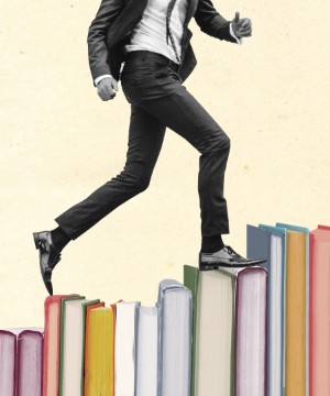 Man in suit walking up spines of books