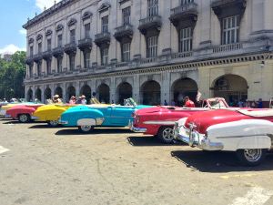 A line of colorful classic cars parked in front of the capitol building in Havana
