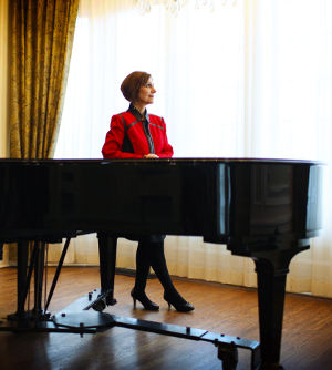 Geri Presti standing beside a piano