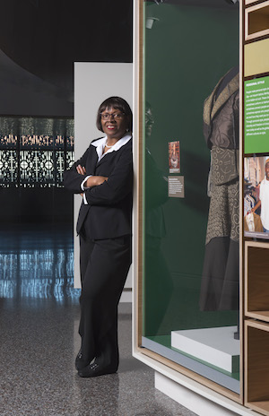A portrait of Elaine Nichols standing near an exhibit at the Smithsonian’s National Musem of African American History and Culture