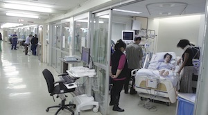 Multiple people standing around a patient in a hospital bed
