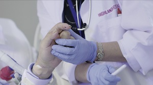 Up-close view of a physician's gloved hand holding the hand of a patient
