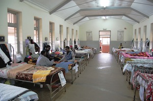 A few patients sitting in beds in a Ugandan hospital ward.