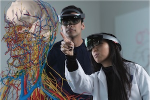 Two students using Microsoft HoloLens headsets looking at a 3D hologram of the human body