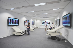 Several students in white coats looking at LED screens in a living anatomy lab on the second floor of the Samson Pavilion