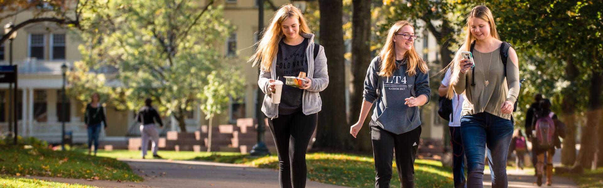 Three students walking through campus on a sunny fall day
