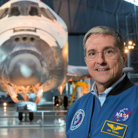 Former CWRU student, Astronaut Don Thomas in front of a shuttle in hangar. 