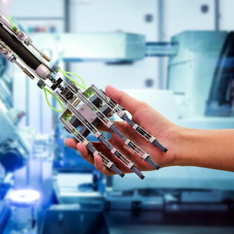 A robotic hand shaking hands with a human hand 