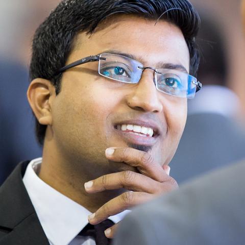 Business student in suit and glasses with one hand on his chin
