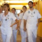A group of nursing students in uniform walking down a hallway smiling