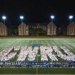Students in white shirts arranged on the football field in such a way that they form the large letters "CWRU"