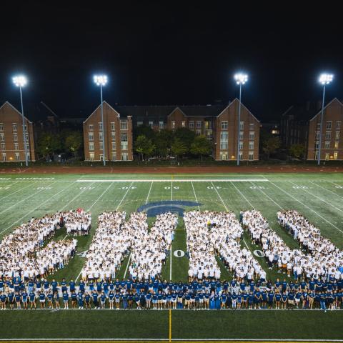 Students in white shirts arranged on the football field in such a way that they form the large letters "CWRU"