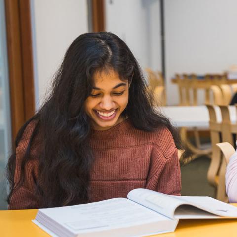 two students studying and smiling
