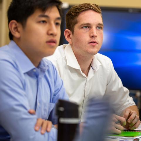 two male students in collared shirts, blue screen in background