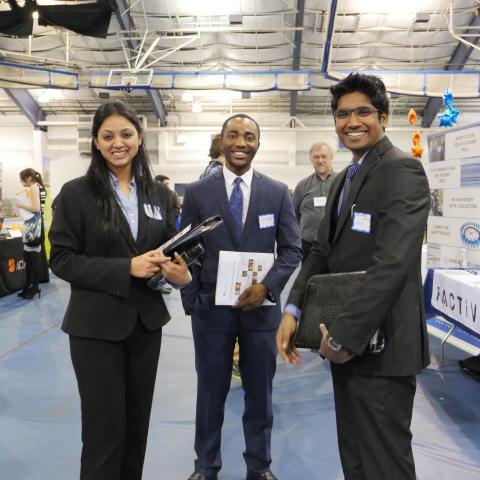 Three students standing and smiling at the career fair