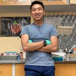 A photo of Ethan Lin posing in a lab with his arms crossed