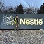 Amos Langsner posing in front of a Nestle sign