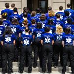 A group of EMS student workers all standing with their backs facing us with a blue EMS shirt on