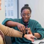 Black female student taking someone's temperature 