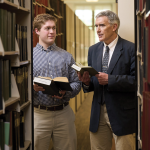 A photo of Carson with a man in a suit in a library 