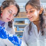 2 female cwru students working in a lab together looking at something they are holding 