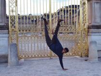 Student does a one-handed handstand in front of castle gates