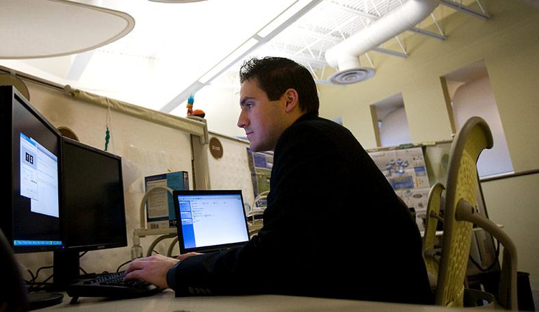 Student working on a computer with two monitors