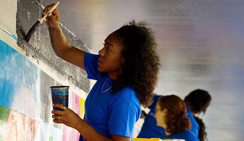 Student volunteering by helping paint a room