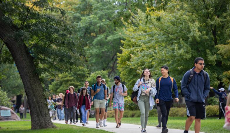 Students walking down a wooded sidewalk.